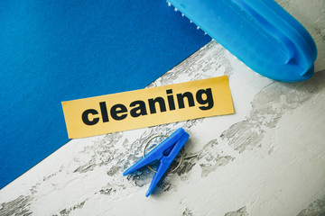Cleaning concept light concrete background with blue cleaning tools and Cleaning inscription, top...