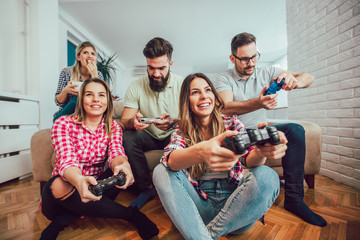 Fototapeta premium Group of friends play video games together at home, having fun.