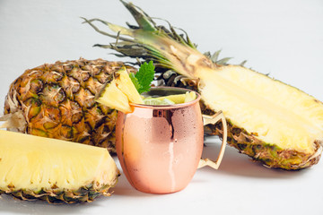 Cold pineapple Moscow Mule cocktail in copper mug on the rustic background. Shallow depth of field.