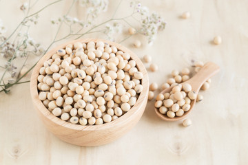 Soybeans in wooden cup and wooden spoon on wood table