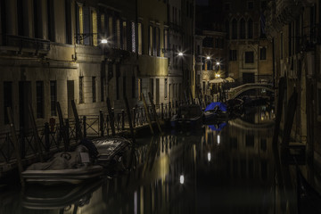 Canal and a small bridge in Venice at night illuminated by lamps, Italy