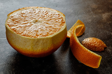 Peeled orange with orange peel on black table close up