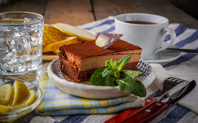Chocolate cake and a cup of tea; water with ice and slices of pear; on background.