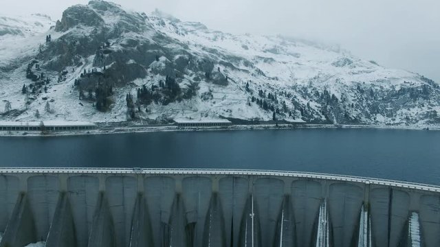 4K video of aerial view Italian Dolomites mountains alps. Foggy winter day in Italy. Car goes in the snowy road by the damb