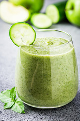 Green protein smoothie in a glass on concrete background. Selective focus, copy space.