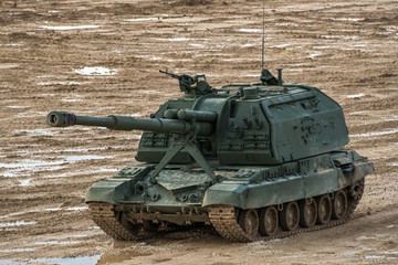 Fototapeta na wymiar Self-propelled howitzer on crawler tracks with rotating turret moving over battle field terrain