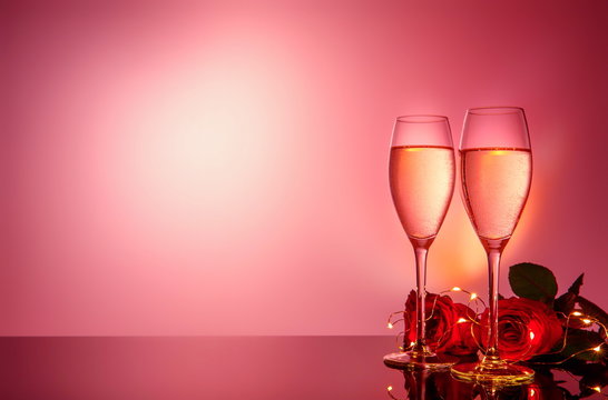 Champagne glasses, present and roses in front of beige background