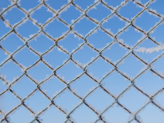 metal grill winter frosty morning on a blue sky background covered with snow