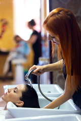 Beautiful young woman washes hair in a beauty salon.