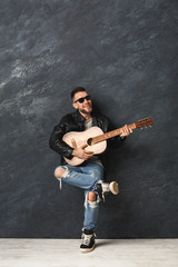 Fototapeta na wymiar Handsome smiling man with guitar posing in studio