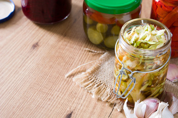 Fermented preserved vegetables in jar on wooden table. Copyspace