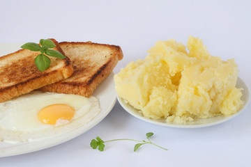 scrambled eggs with herbs and toasts on the white porcelain plate, mashed potatoes, white background
