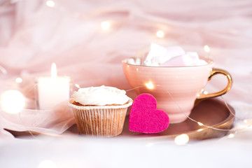 Cupcake with pink heart nd cup of coffee in bed close up. Valentines day. Good morning.