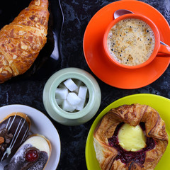 Orange mug with coffee, cake and a croissant