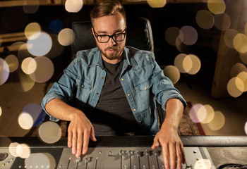 man at mixing console in music recording studio