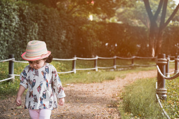 little baby girl with colourful hat and dress walking alone