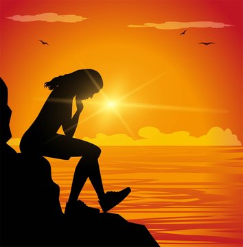 Sad girl sitting on a cliff facing the sea