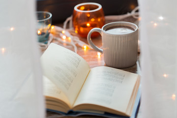 book and cup of coffee or hot chocolate on table