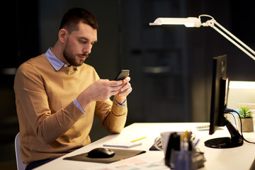 man with smartphone working late at night office