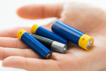 close up of hands holding alkaline batteries heap