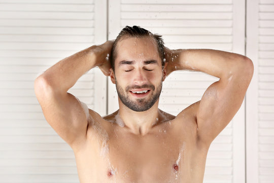 Young handsome man taking shower in bathroom