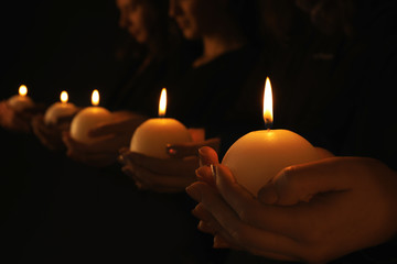 Young people with burning candles in darkness