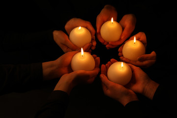 Young people with burning candles in darkness