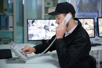 Male security guard talking by telephone in surveillance room