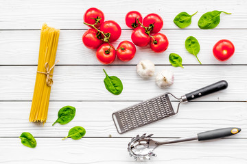 Fototapeta na wymiar Cook spaghetti with tomatoes, garlic, basil. Italian recipe. White wooden background top view