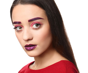 Young woman with dyed eyebrows and creative makeup on white background