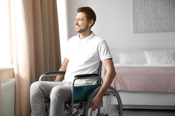 Young man in wheelchair near window indoors