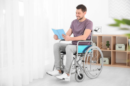 Young man in wheelchair reading book indoors
