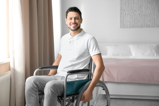 Young man in wheelchair near window indoors
