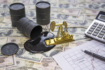 The concept of the oil business. Barrels of oil are worth a dollar money banknote, a gold drilling pump, a calculator, a growth chart of products and imports