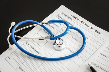 Health insurance form and stethoscope on table, closeup
