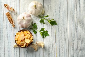 Bowl with dried garlic flakes on wooden background