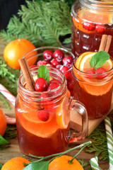 Punch with cranberries and orange decorated with mint and a stick of cinnamon in glass vessels