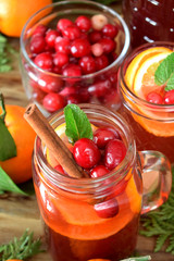 Punch with cranberries and orange decorated with mint and a stick of cinnamon in glass vessels