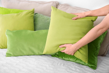 Woman putting pillow on bed, closeup