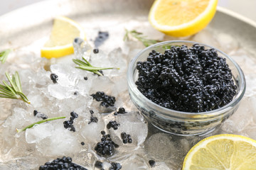Black caviar served with ice and lemon on metal plate