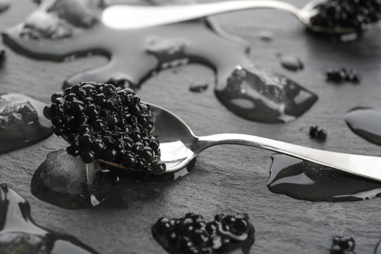 Spoon with black caviar on grey background