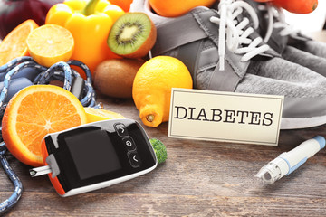 Digital glucometer, lancet pen and fruits on wooden background. Diabetes diet