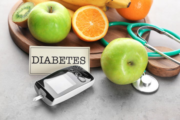 Digital glucometer and fruits on grey background. Diabetes diet