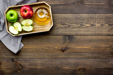 Light salad dressing. Apple cider vinegar in bottle among fresh apples on dark wooden background top view copy space