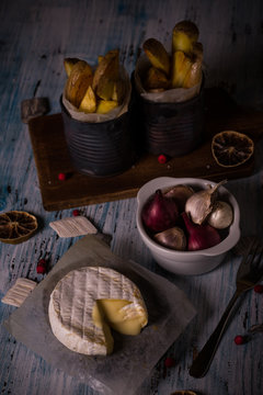 Melted camembert cheese on wooden board with onions and fried potato stripps