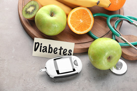 Digital glucometer and fruits on grey background. Diabetes diet