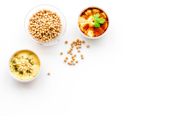 Middle Eastern cuisine. Bowls with hummus and chickpeas on white background top view copy space