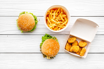 Most popular fast food meal. Chiken nuggets, burgers and french fries on white wooden background top view