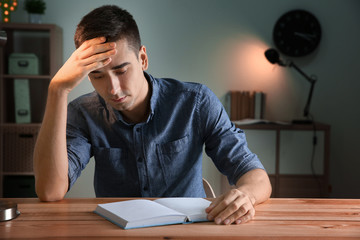 Male student preparing for exam at table indoors