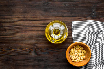 Oil for skin care. Peanut oil near peanut in shell on dark wooden background top view copy space